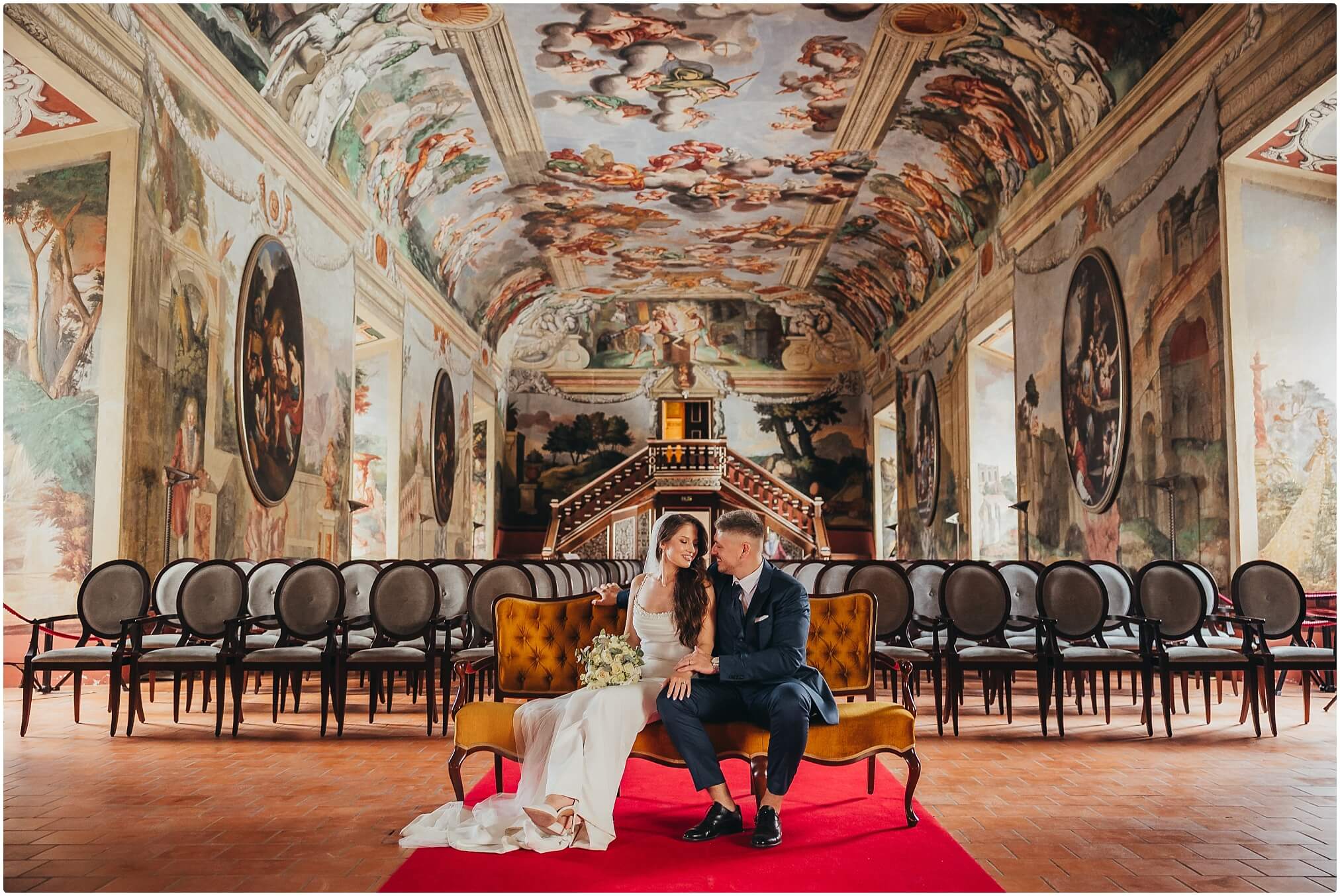 Vjenčani par zagrljen na stepenicama dvorca u elegantnoj atmosferi